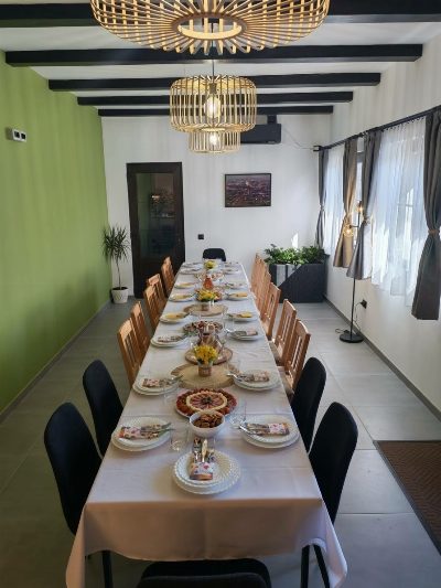 Sală de mese comună la cazarea Somni din Chinteni, cu masa lungă pregătită pentru un eveniment restrâns.