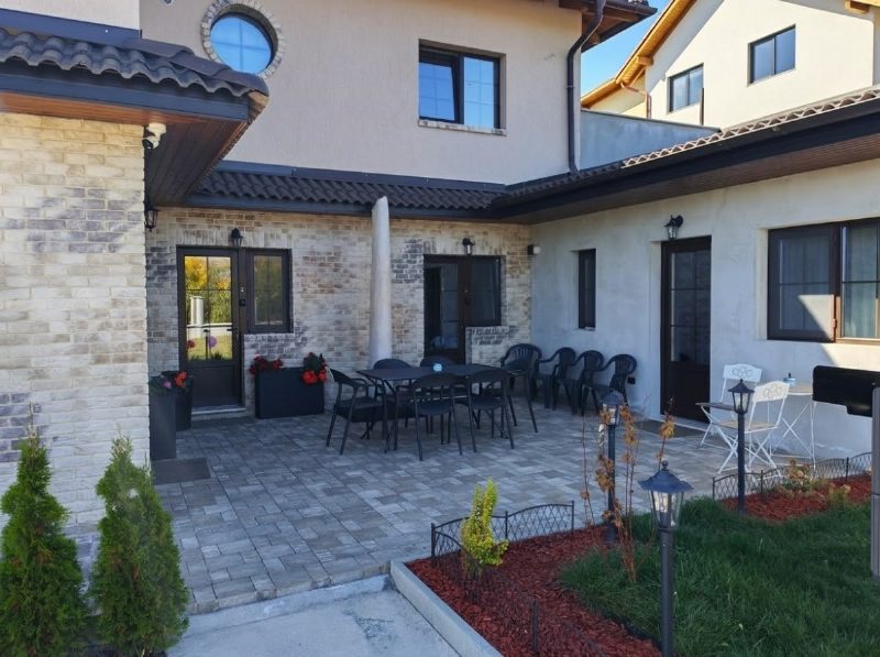 Közös terasz a kajántói Somni apartmanok előtt, asztallal és kerti székekkel.